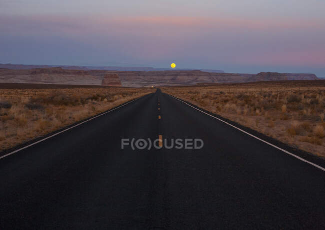 Wüstenstraße in der Abenddämmerung bei Mondaufgang, Arizona, USA — Stockfoto