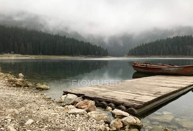 Vecchia barca di legno al vecchio molo di legno sul lago nero in Montenegro. — Foto stock