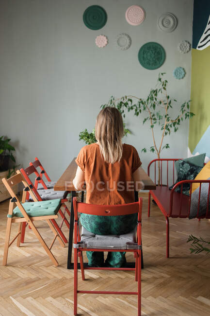 Mulher senta-se de volta à mesa com cadeiras vazias ao lado no escritório moderno — Fotografia de Stock