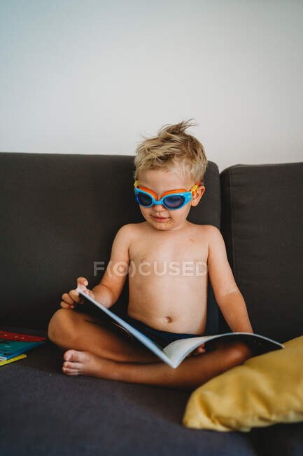 Joven niño leyendo en topless con gafas para la educación en casa - foto de stock