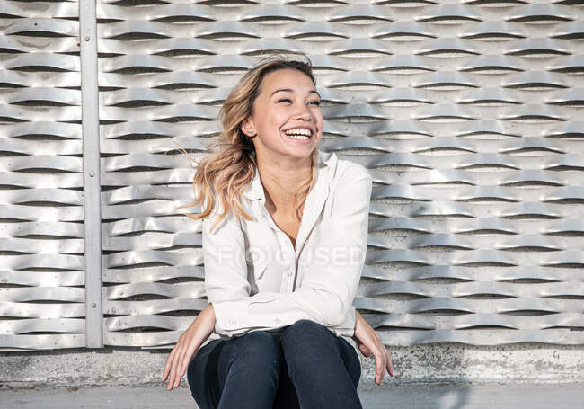 Портрет молодой женщины с большой улыбкой перед металлической стеной — стоковое фото