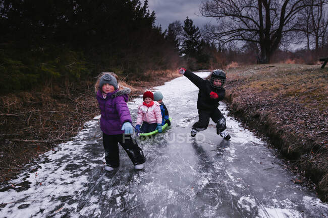 Маленькие дети катаются на коньках по пруду зимой — стоковое фото
