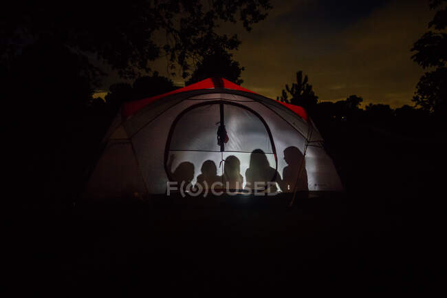 Family camping in backyard in tent lit with flashlight — Stock Photo
