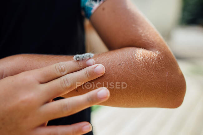 Tiny white and furry caterpillar crawling on girls finger — Stock Photo