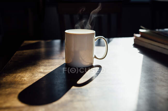 Кружка белого кофе в утреннем свете с паром — стоковое фото