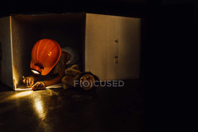 Kleiner Junge mit Stirnlampe und Zeichnung in Schachtel mit Stofftier — Stockfoto