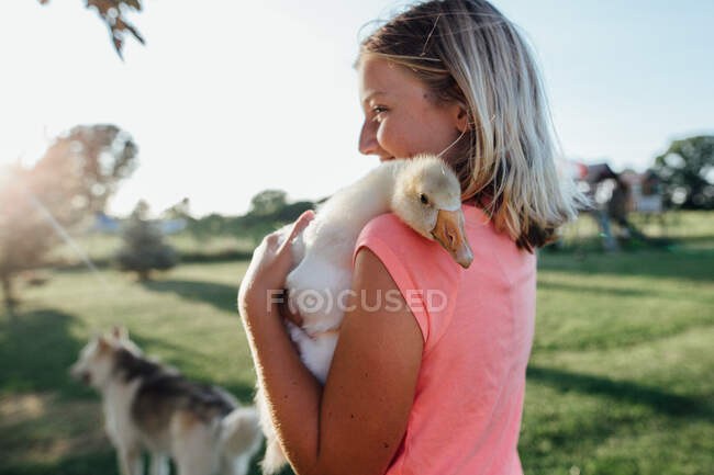 Smiling Girl holding duckling on farm — Stock Photo