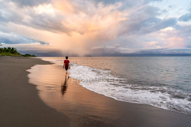 Teenager walking on beautiful beach at sunset — Stock Photo