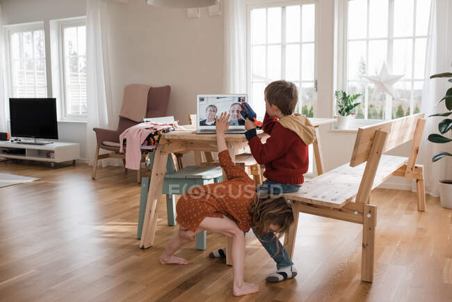 Дети показывают своим бабушке и дедушке свои игрушки посредством видеозвонка в изоляции — стоковое фото