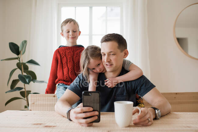 Padre y sus hijos que tienen una videollamada desde casa en aislamiento - foto de stock