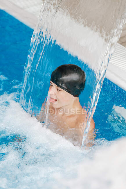 Young teenager enjoying under a waterfall jet in a spa — Stock Photo