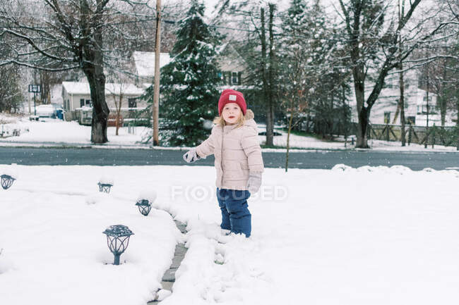 Kleines Kind räumt den Schnee von den Solarlampen auf ihrem Hof. — Stockfoto