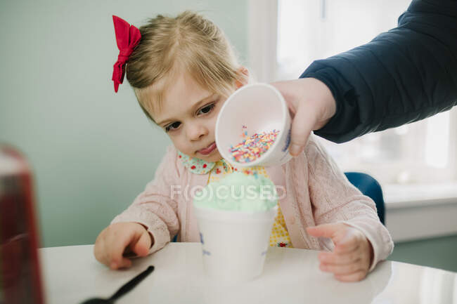 Mutter gießt Streusel auf Mädchen-Eis — Stockfoto