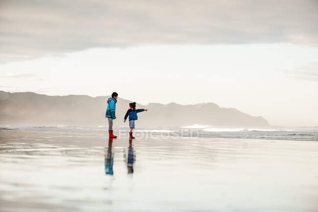 Hermanos en la playa en Nueva Zelanda en el día de invierno - foto de stock