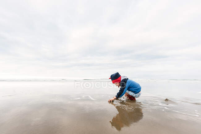 Дошкольник играет на пляже зимой — стоковое фото