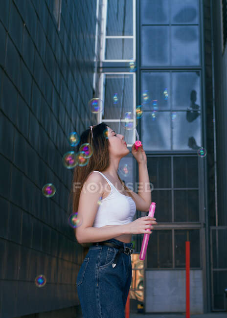 A young girl has fun making soap bubbles in a big city alley — Stock Photo