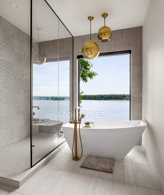 Atemberaubendes Badezimmer in neuen zeitgenössischen Stil Luxus-Haus mit Fliesen, Boden, Pendelleuchten, Badewanne mit erstaunlichem Blick auf das Wasser — Stockfoto
