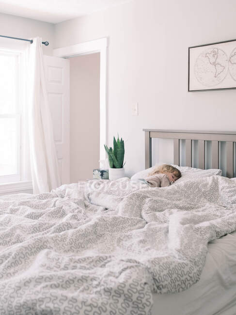 Ein Kleinkind schläft im Bett seiner Eltern mit einem Schnuller. — Stockfoto