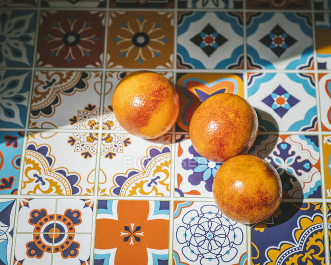 Апельсины на красочном керамическом столе, под солнцем — стоковое фото