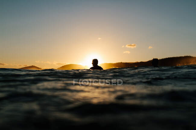Силует серфера, що сидить у воді на заході сонця — стокове фото