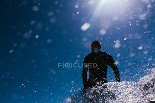 Surfer in action in a blue sky filled with water droplets — Stock Photo