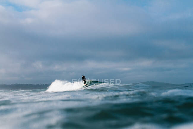 Surfista sozinho surfando uma pequena onda em um vasto oceano — Fotografia de Stock