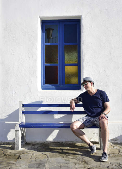 Турист в Миконосе на скамейке с окном — стоковое фото