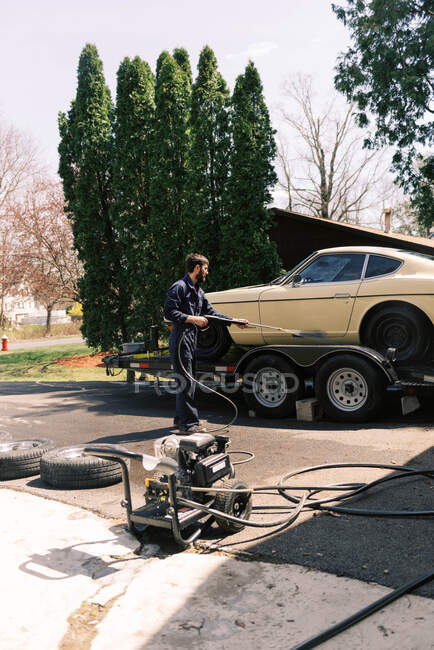 Ein Millennial-Männchen mit einer Waschmaschine, um sein Auto zu reinigen. — Stockfoto