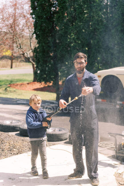 A millennial male using a power washer to clean suds off his hands. — Stock Photo