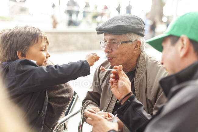Grandson and grandfather sharing ice cream — Stock Photo