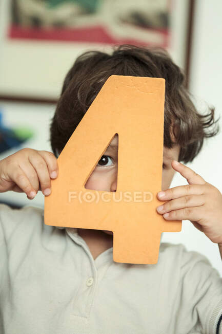 Niño pequeño sosteniendo un número de espuma en sus manos - foto de stock