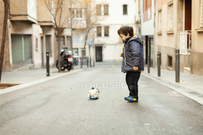 Menino com puxar cordão cão brinquedo na rua Barcelona — Fotografia de Stock