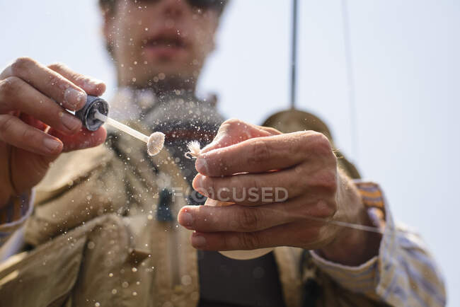 Angler getting a dry fly ready. — Stock Photo