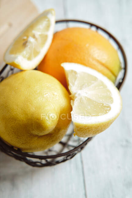 Orange and lemon in basket on wooden background — Stock Photo