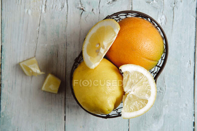 Laranja e limão em cesta no fundo de madeira — Fotografia de Stock