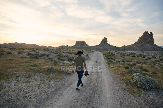 Joven senderismo al anochecer en el desierto. - foto de stock