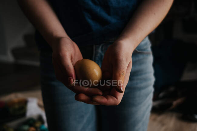 Vista frontale della ragazza più grande che tiene un uovo di pollo tinto giallo — Foto stock
