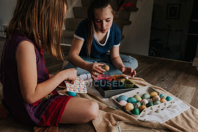Sisters dying chicken eggs inside the house — Stock Photo