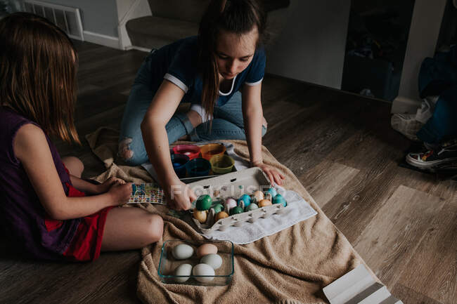 Sisters sitting inside dying easter eggs together — Stock Photo