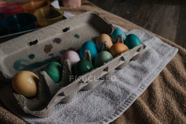 Painted eggs in container, towels background — Stock Photo