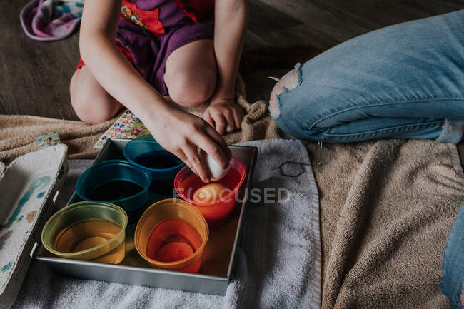 Faceless image of siblings dying chicken eggs for easter — Stock Photo