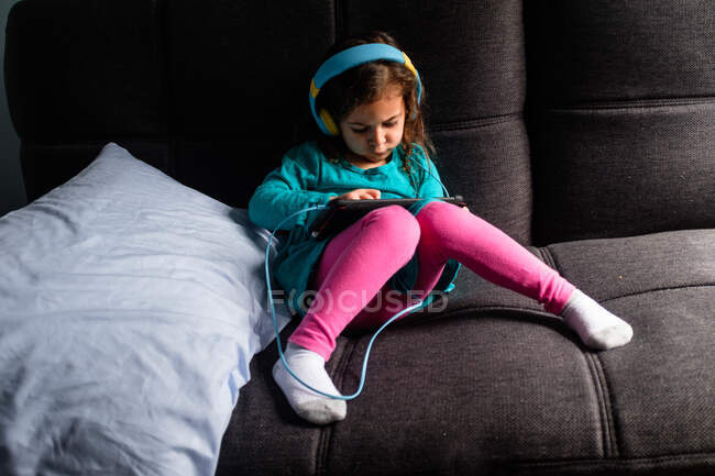 Молода дівчина грає в iPad гру на дивані. — стокове фото