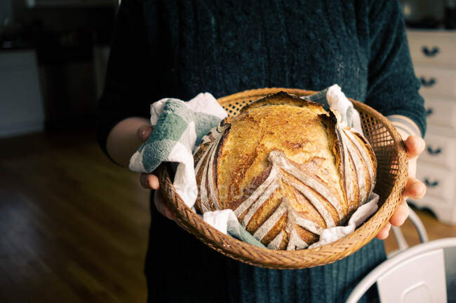 Woman proudly holding her homemade sourdough bread. — Stock Photo