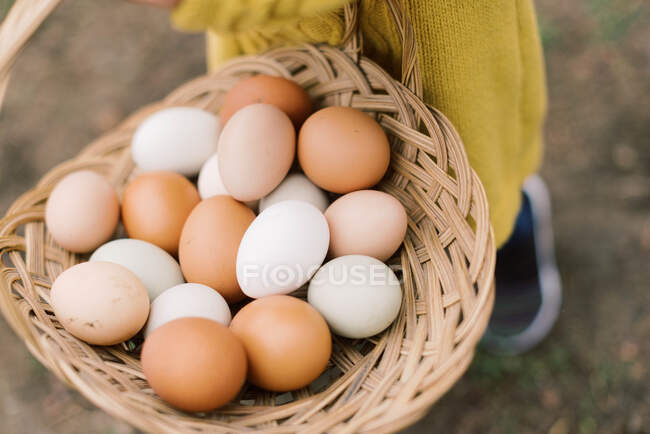 Ovos em uma cesta em um fundo de madeira — Fotografia de Stock