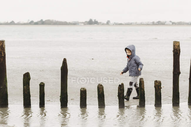 Boy walking on cold winter beach — Stock Photo