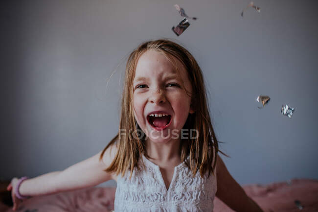 Portrait of young girl happily throwing silver confetti — Stock Photo
