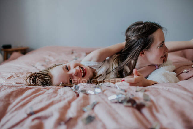 Irmãs deitadas em uma cama brincando juntas — Fotografia de Stock