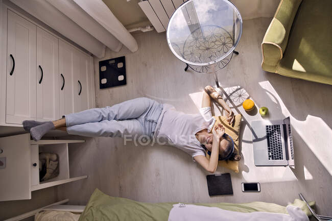 Jeune femme couchée sur le sol à la maison avec ordinateur portable — Photo de stock