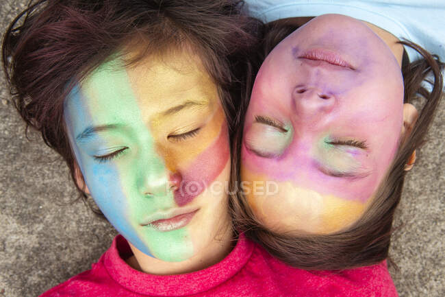 Two peaceful children in face paint lay together with eyes closed — Stock Photo