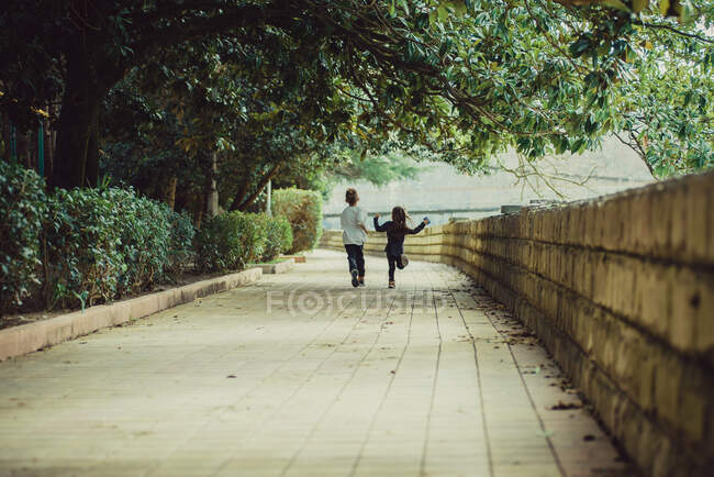 Dos niños felices huyendo de la cámara - foto de stock